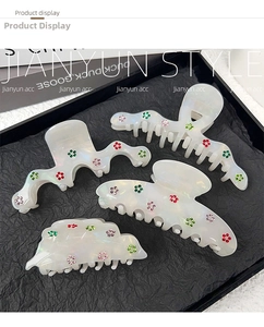 Detail of four acetate claw clips with pearl white finish and colorful rhinestone flowers