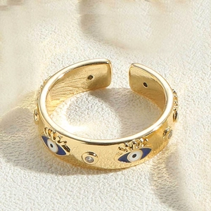 Macro detail of 14K gold plated open ring featuring blue and white zircon evil eye motifs