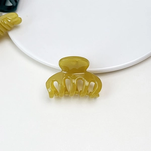 Macro shot of a translucent mustard yellow jelly hair claw clip on a white round base