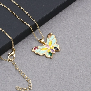 Detailed macro view of bohemian gold butterfly pendant with colorful enamel and inset gems