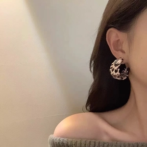 Retro C-shape leopard print earrings on Asian model in warm indoor natural lighting