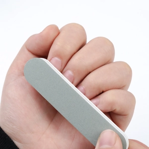 Close-up of double-sided grey sponge nail file buffer showing flexible foam layer