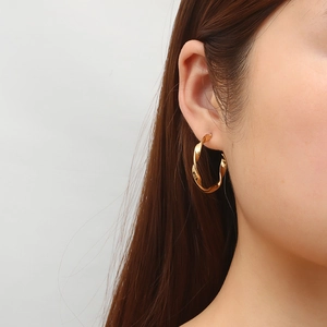 Élégantes boucles d'oreilles créoles torsadées en acier inoxydable doré 18 carats sur mannequin