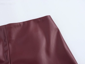 Detail of the high-waist burgundy PU leather mini skirt showing its glossy texture