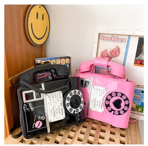 Close-up of retro pink and black telephone handbags with shiny patent leather texture