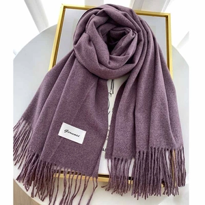 Detailed close-up of soft thick purple scarf featuring fringe ends and a woven label