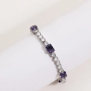 Macro view of silver tennis bracelet with emerald-cut purple stones and white zircons