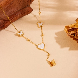 Gold butterfly and white heart pendant necklace in shell finish on textured surface