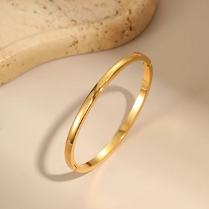 Macro detail of high-polish mirror finish on a minimalist gold stainless steel bangle