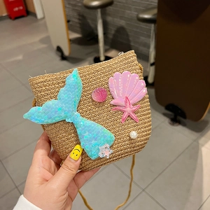 Detail of straw woven crossbody bag with mermaid tail shell and pearl decorations