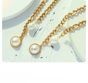 Detail of 18k gold plated choker with baroque pearl pendant on textured stone base