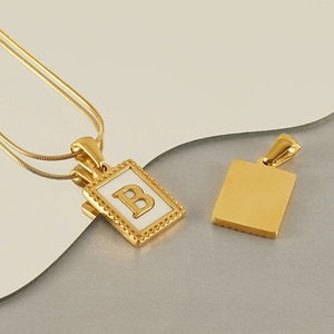 Detail of a gold snake chain necklace featuring a square pendant with letter B design