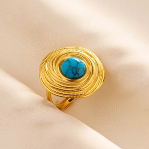 Detail of bohemian gold spiral ring featuring a round blue turquoise on beige fabric