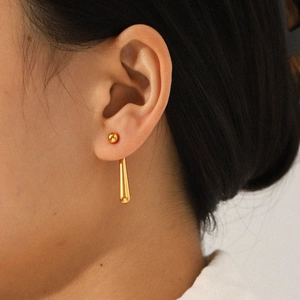 Detailed view of 18K gold drop earrings with metallic spheres on female model