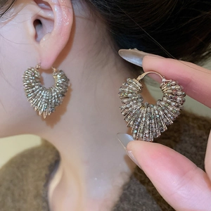 Detailed macro of heart shaped beaded hoop earrings with metallic crystal textures