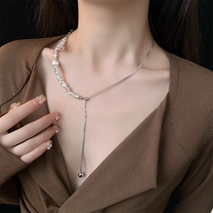 Detailed view of silver Y-shaped baroque pearl necklace with textured beads on model