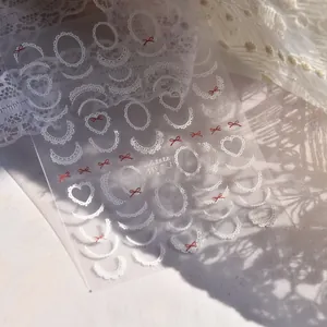 Detail shot of MS723 nail stickers featuring white lace patterns and red bows on clear film