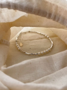 Macro view of S925 silver irregular beads and pearls on an elegant textured fabric bag