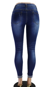 Detail der blauen Stretch-Jeans mit abgenutzten Taschen und aufgerollten rohen Säumen