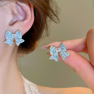 Close-up of light blue butterfly stud earrings with crushed ice texture and rhinestones