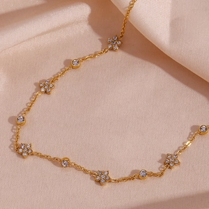 Detail of gold chain necklace featuring zircon-encrusted flowers on beige silk