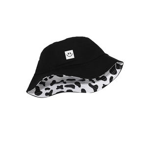 Reversible bucket hat featuring black smile patch and cow print for sun protection