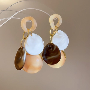 Detail of geometric acrylic tassel earrings with tortoiseshell pattern and gold rings