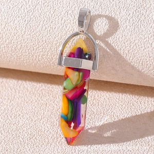 Macro shot of a bullet-shaped resin pendant filled with colorful fragments on a textured base