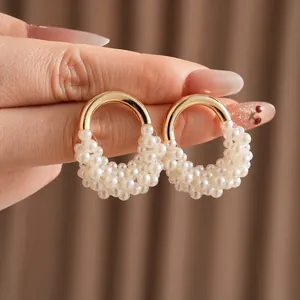 Orecchini vintage a forma di U in oro con perle presentati tenuti tra le dita