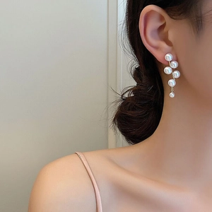 Close-up of elegant gold C-shaped pearl drop earrings with zircon accents on model