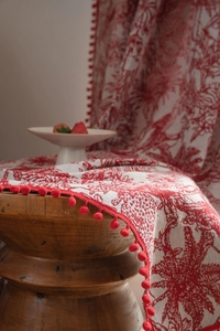 Detailed view of red Toile de Jouy print fabric with decorative pompom fringe