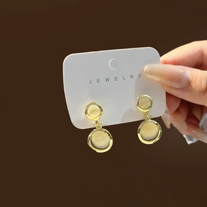 Macro detail of French style gold hoop earrings with cat-eye stone and zircons
