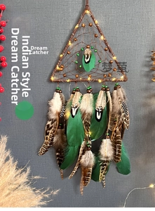 Detail of triangular dreamcatcher with warm LED lights and feathers hanging on a textured wall