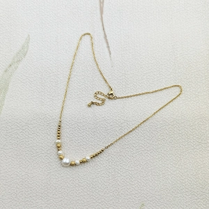 Detailed view of the lobster clasp and adjustable chain on the gold pearl necklace