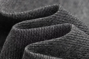 Macro shot of high-quality charcoal gray herringbone wool blend fabric with twill texture