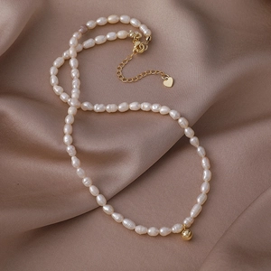 Detalle del collar de perlas de agua dulce con colgante de corazón dorado en seda champán