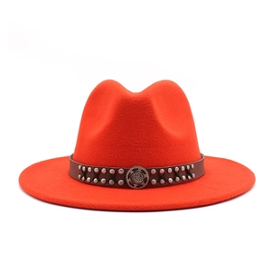 Orange felt jazz hat with wide brim and decorative studded leather band on white background