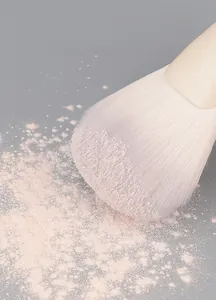 Macro detail of soft powder brush bristles picking up loose pink cosmetic powder