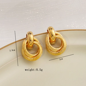 Macro shot of geometric gold earrings with dimensions 2.9cm by 2cm on ceramic plate