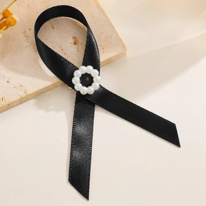 Détail d'une élégante broche en ruban noir avec anneau de perles sur pierre texturée