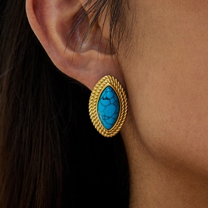 Close-up of a gold rope twist earring with blue turquoise stone worn on the ear