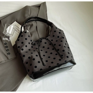 Detail view of dark grey canvas tote with black polka dots on a blazer background