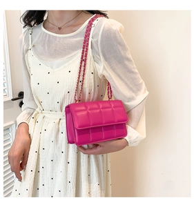 Detail of rose red quilted crossbody bag featuring a golden chain strap and PU leather texture