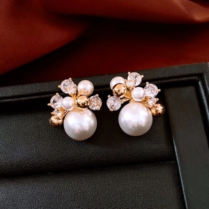 Detailed close-up of 18K gold plated pearl stud earrings with sparkling cubic zirconia