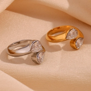 Macro shot of gold and silver open rings with double pear-cut cubic zirconia on beige fabric