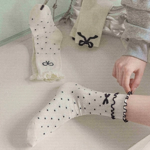 Detail of cream mid-calf socks with black polka dots and 3D bowknot ribbon accents