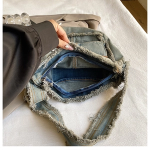 Close-up of blue washed denim bag featuring fringe edges and internal zipper pocket