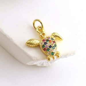 Macro shot of gold-plated sea turtle pendant with colorful zircon stones on shell