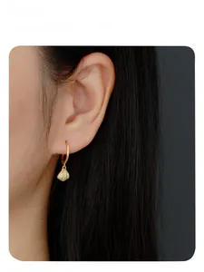 Close-up of gold seashell hoop earrings with sparkling zircons on female model