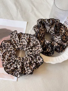 Dettaglio di elastici scrunchie leopardati con bordino nero su piatto di ceramica
